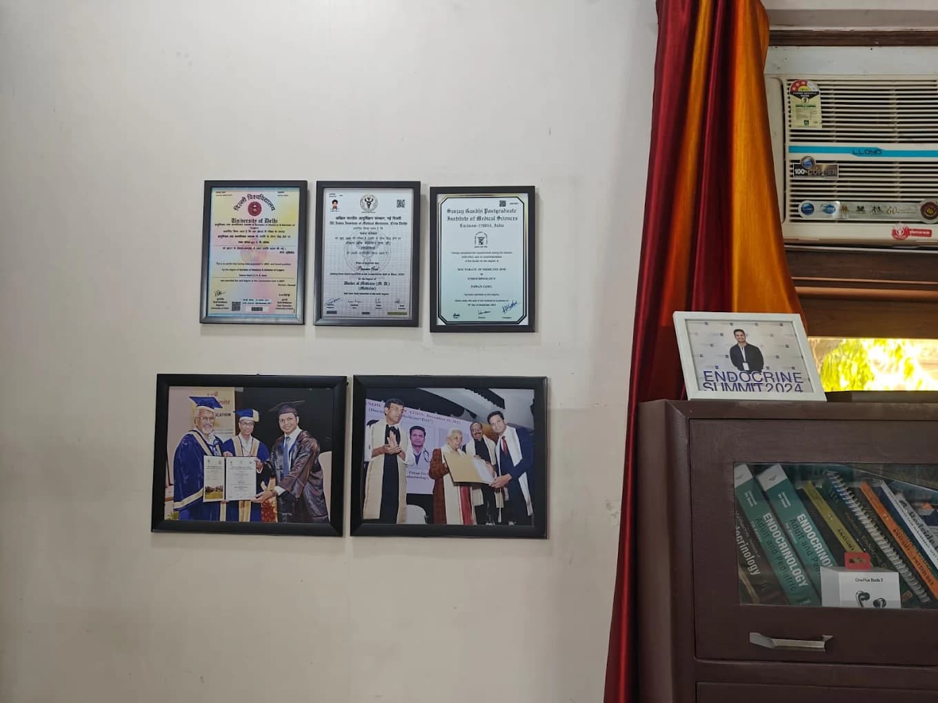 Framed medical degrees and graduation photographs on the clinic wall